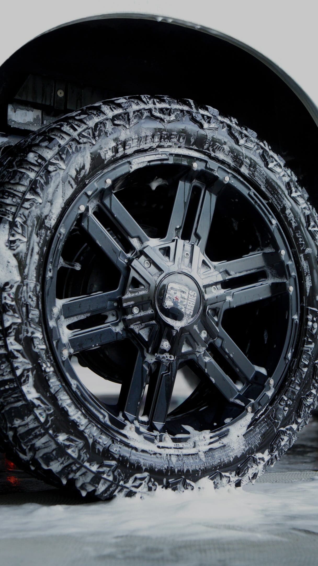 Snow foam on an off-road tyre and black alloy wheel