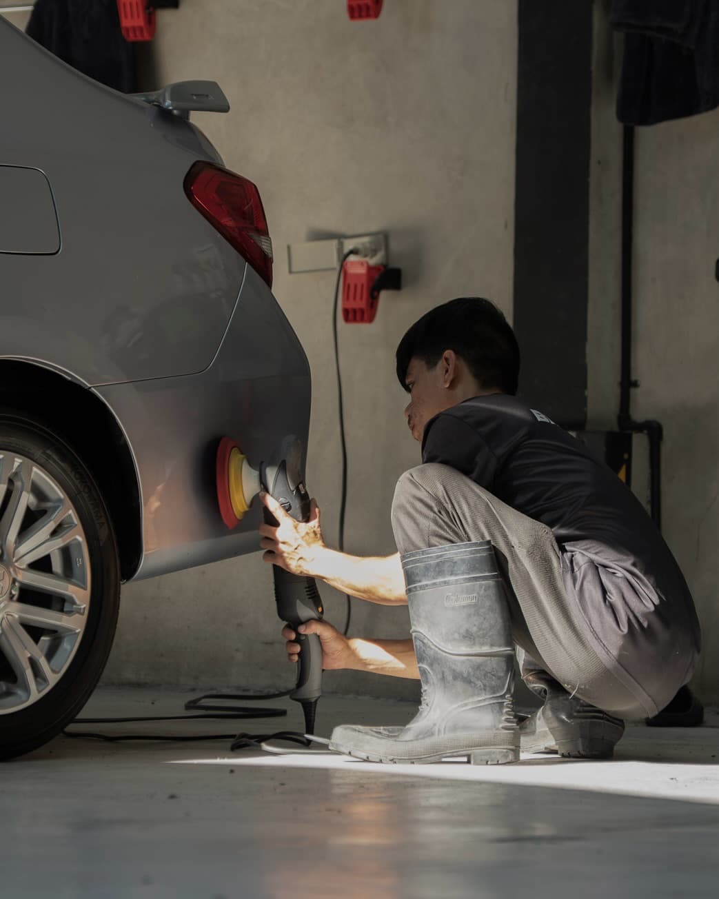 Technician machine-polishing a silver car at BNT Garage